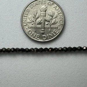 Black beads next to US dime.