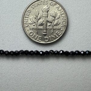 Black beads beside a US dime.