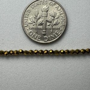Gold beads beside US dime for scale.