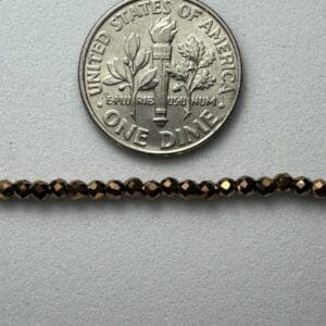 Bronze beads next to dime for scale.