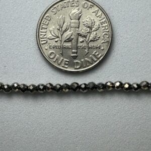 Black gemstone beads with dime for scale.