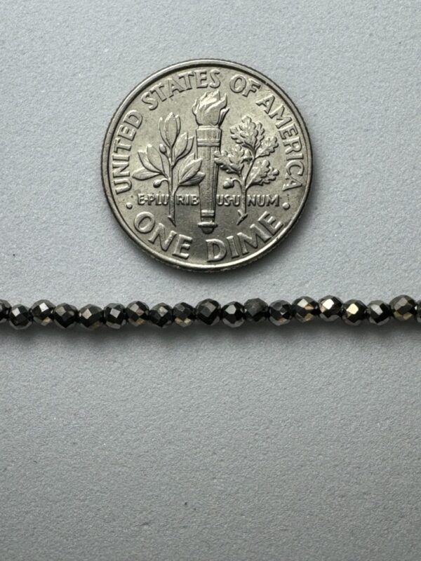 Black gemstone beads with dime for scale.