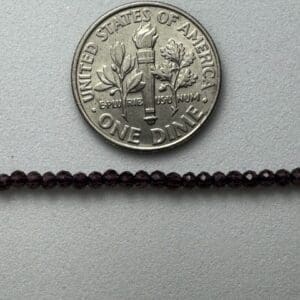 Dime next to dark purple beads.