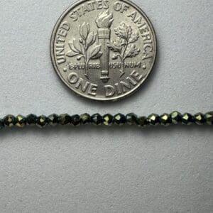 Dark green beads beside a dime.