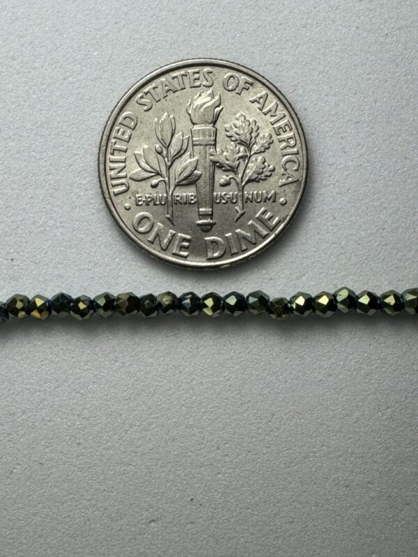 Dark green beads beside a dime.