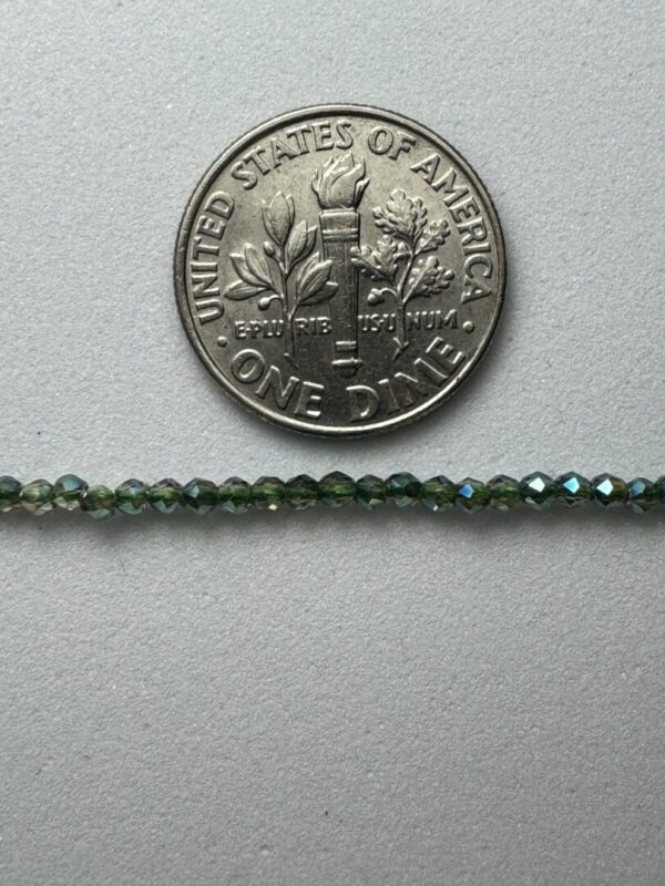 Green glass beads next to dime.