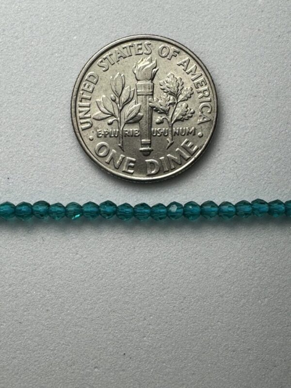 Teal glass beads beside a dime.