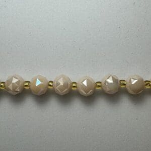 Beige faceted beads with gold spacers.