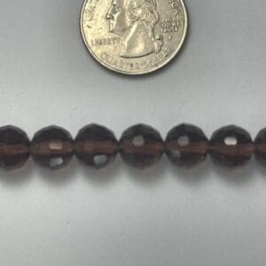 Smoky quartz beads next to quarter.