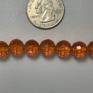 Amber faceted beads with quarter for scale.