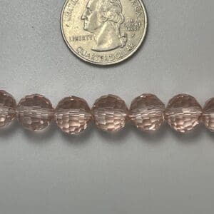 Pink glass beads with quarter for scale.