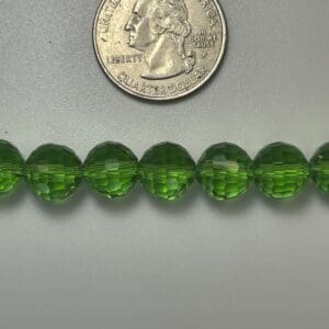 Green glass beads next to quarter.