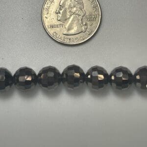 Black faceted beads with quarter for scale.