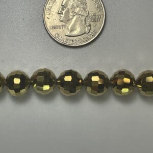 Gold faceted beads with quarter for scale.
