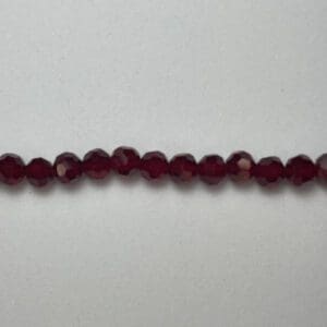 Here's a short alt tag for the image: Dark red faceted glass beads.