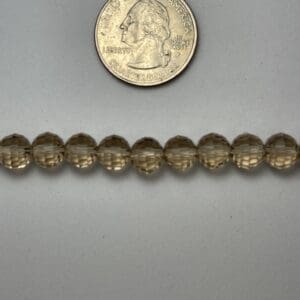 Light brown glass beads with quarter for scale.