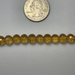 Amber gemstone beads with quarter for scale.