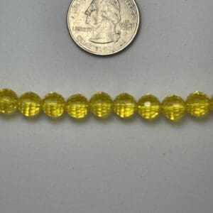 Yellow glass beads next to quarter.