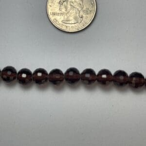 Dark brown faceted beads with quarter for scale.