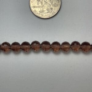 Brown glass beads next to quarter.