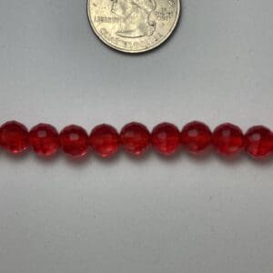 Red glass beads with quarter for scale.