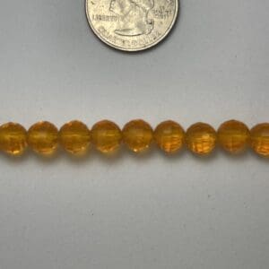 Amber glass beads next to quarter.