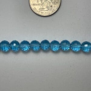 Light blue glass beads next to quarter.
