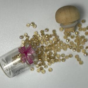 Glass jar with gold beads and wooden top.