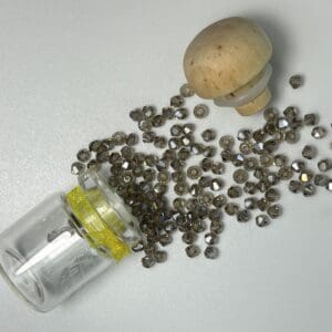 Spilled dark gray glass beads in jar.