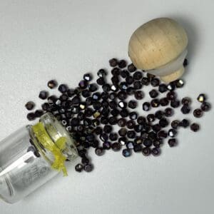 Dark glass beads spilling from jar.