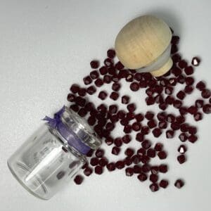 Red glass beads in jar and wooden top.
