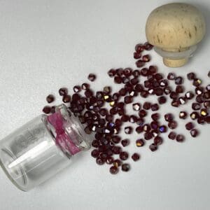 Red glass beads spilling from jar.