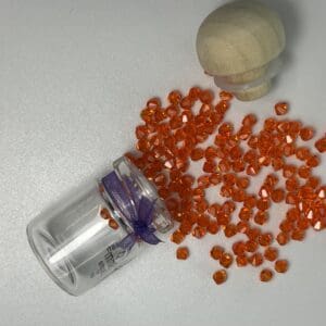 Orange glass beads spilling from jar.