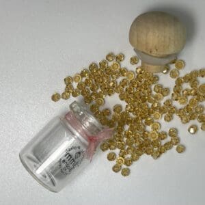 Tipped glass vial spilling faceted golden beads