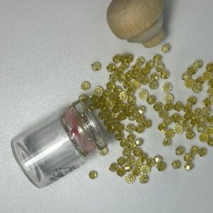 Small glass jar spilling faceted yellow beads