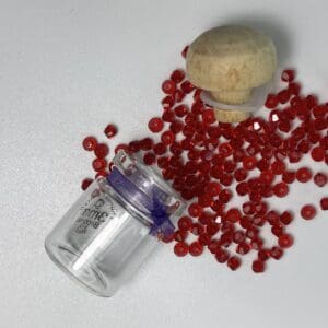 Red glass beads in small jar with cork.