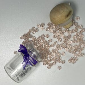Pink beads in jar with wooden lid.