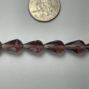 Brown pear-shaped beads with quarter for scale.