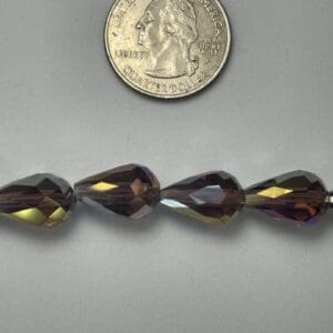 Purple iridescent glass beads near quarter.