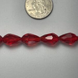 Red glass beads next to quarter.