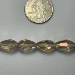 Brown glass beads next to quarter.