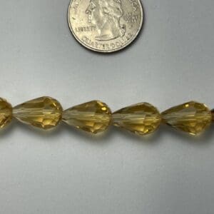 Amber teardrop beads with quarter for scale.
