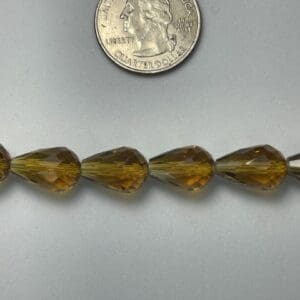Amber teardrop beads with quarter for scale.