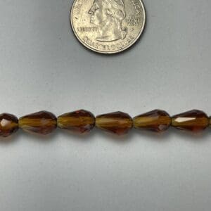 Amber teardrop beads with quarter for scale.
