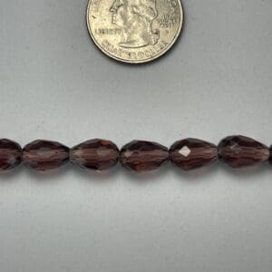 Dark brown faceted beads with quarter for scale.