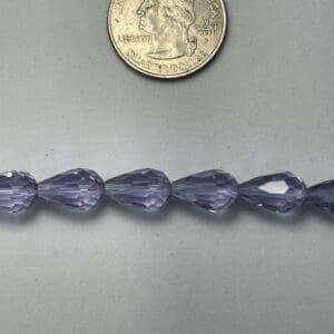 Purple teardrop beads next to a quarter.