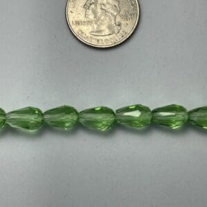 Green glass beads next to quarter.