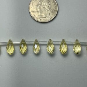 Seven pale yellow faceted teardrop beads.