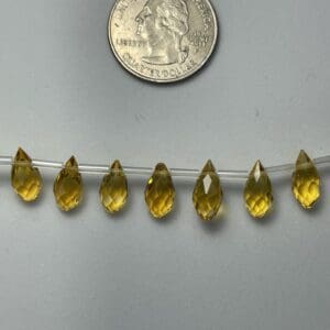 Seven golden teardrop gemstone beads.
