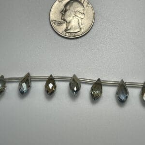 Faceted teardrop beads with quarter for scale.